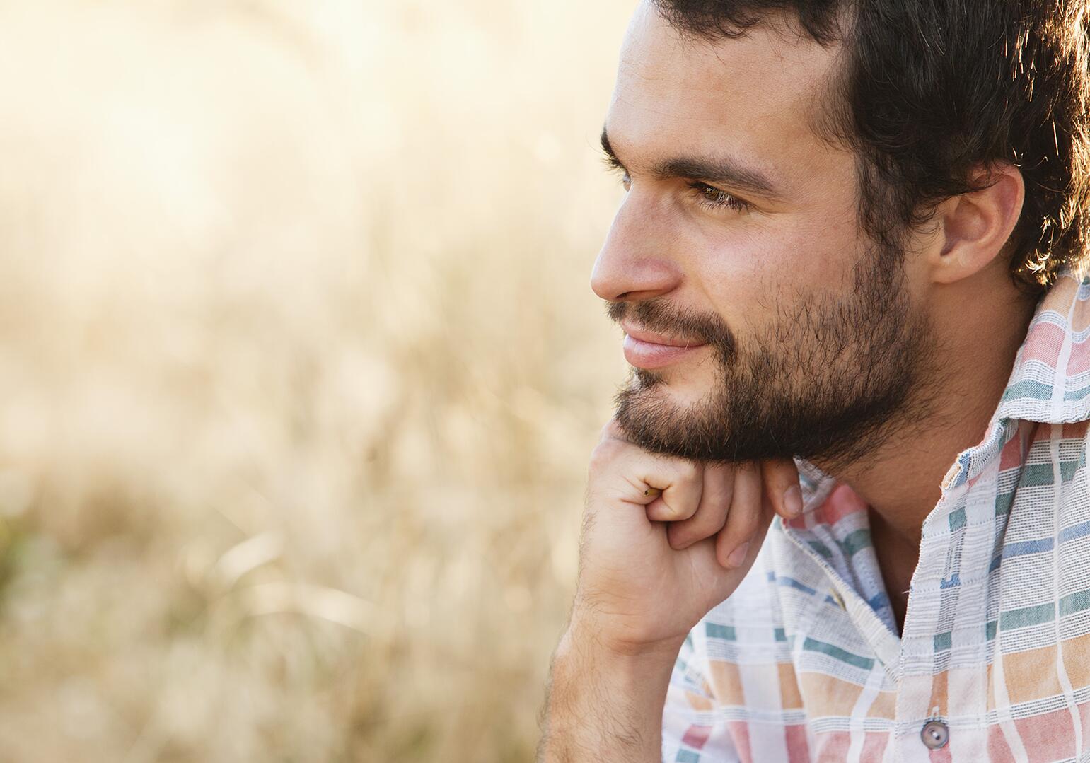 Man in field, deep in thought, smiling